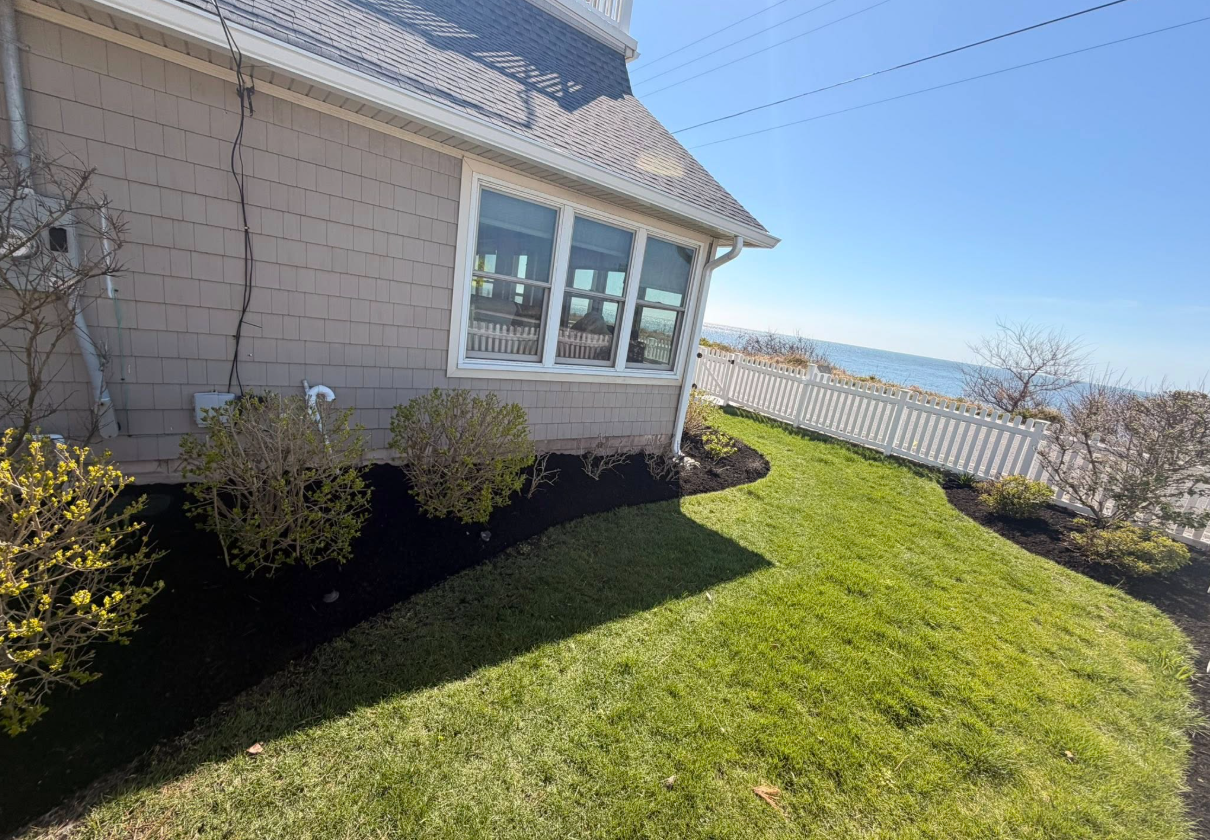 Oceanfront property with manicured lawn and landscape beds